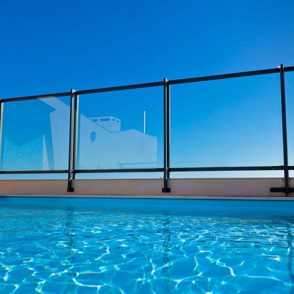 A swimming pool with a glass railing and a blue sky in the background