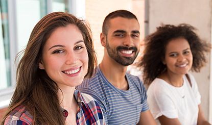 Three smiling people sitting together outdoors.