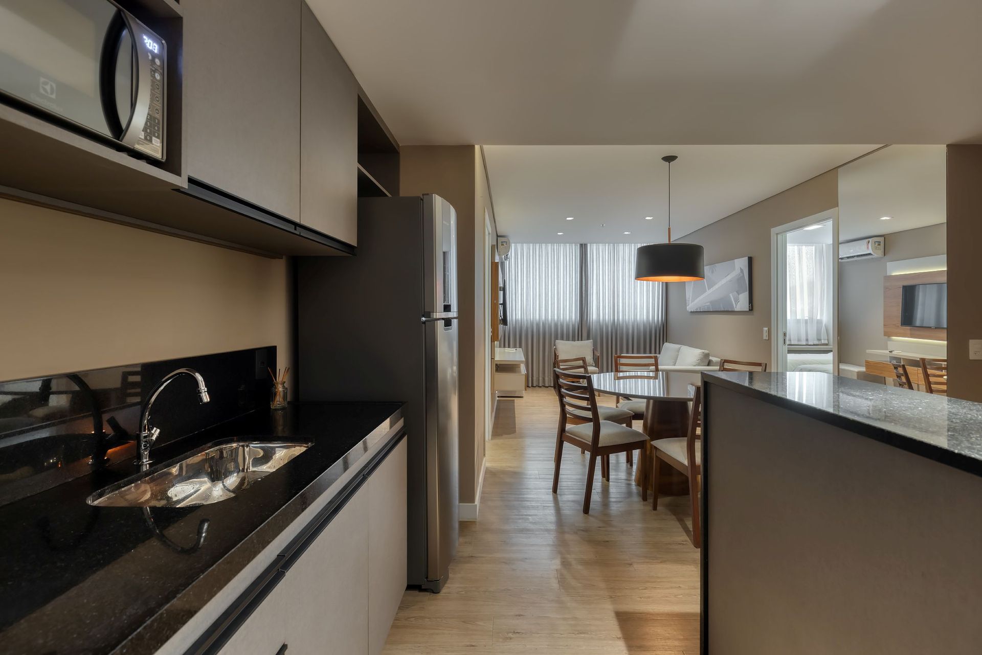 Uma cozinha com pia, geladeira, micro-ondas e mesa de jantar.