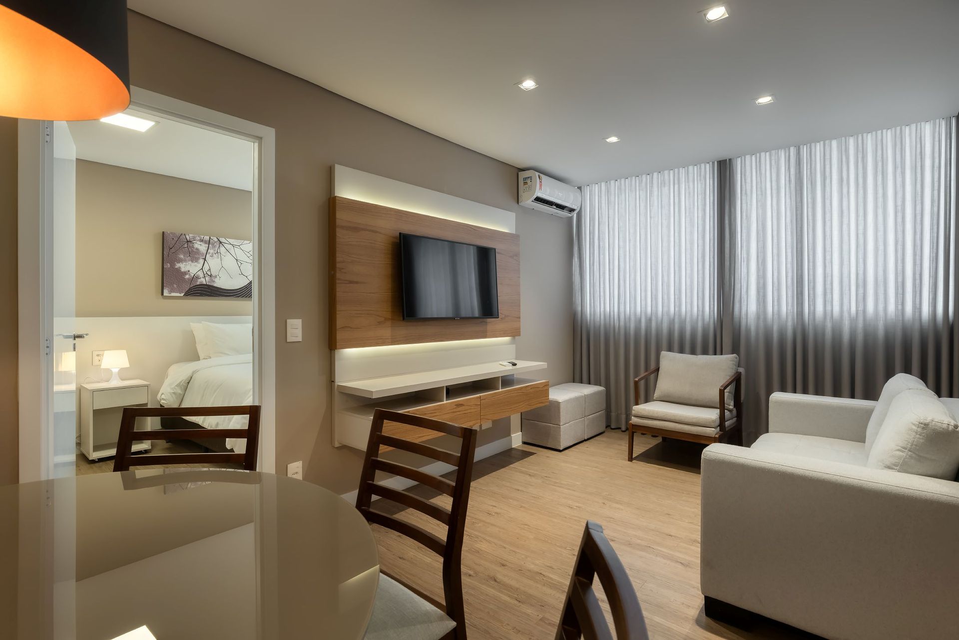 Uma sala de estar com sofá, cadeira, mesa e televisão.