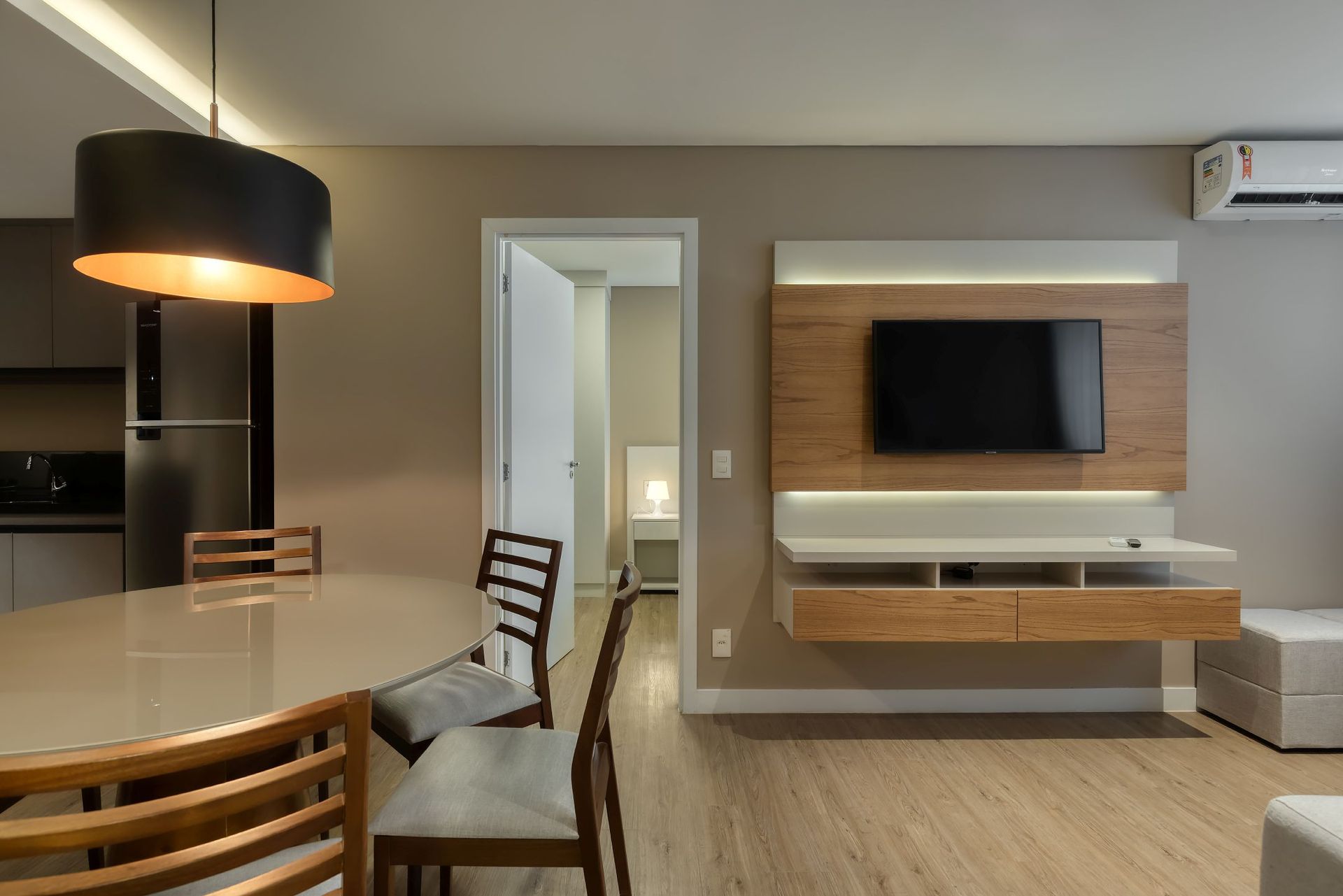 Uma sala de estar com mesa, cadeiras e uma TV de tela plana.