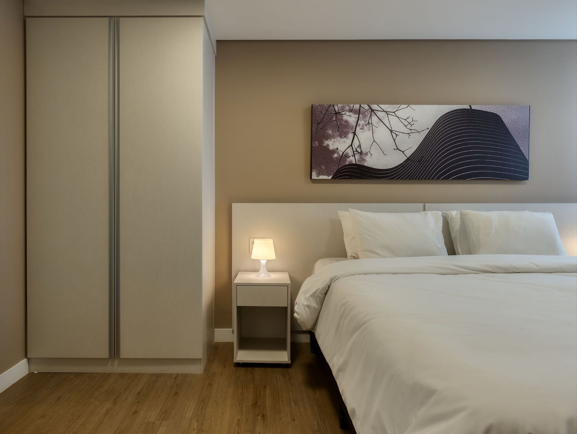 Um quarto com uma pintura na parede acima da cama