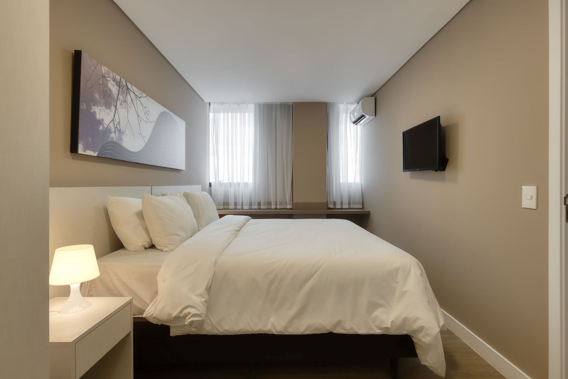 Um quarto com uma cama king size e uma TV de tela plana na parede.