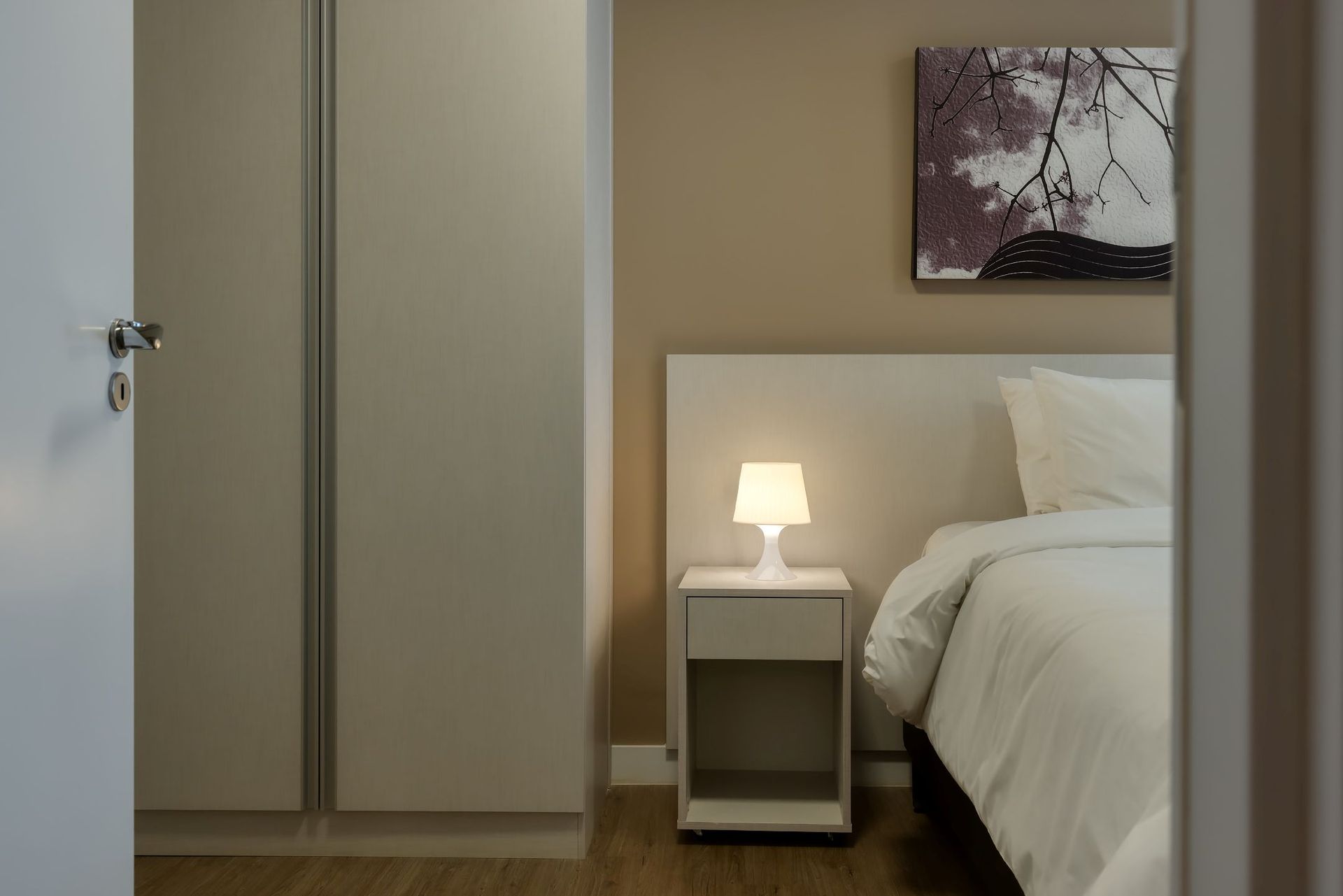 Um quarto com uma cama, uma mesa de cabeceira e um candeeiro