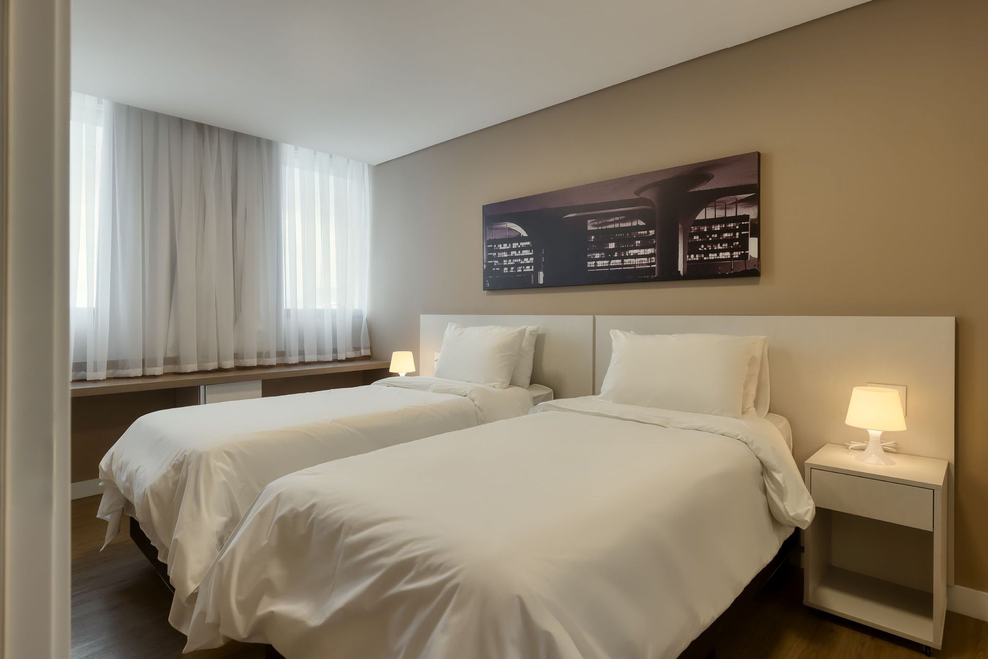 Um quarto de hotel com duas camas e uma mesa de cabeceira.