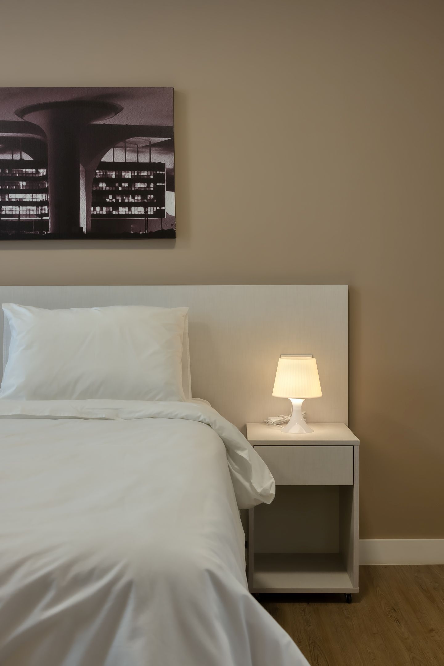 Um quarto com uma cama, uma mesa de cabeceira e um candeeiro