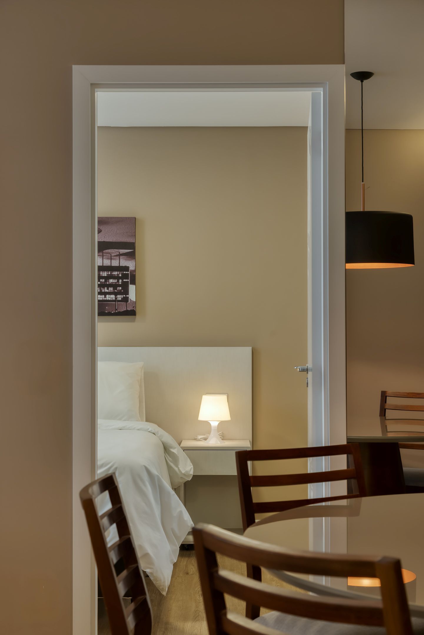 Um quarto com uma mesa e cadeiras e um abajur na mesa de cabeceira