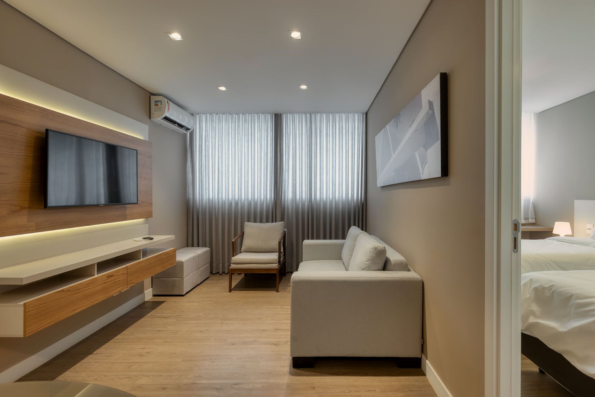 Uma sala de estar com um sofá, uma cadeira e uma televisão.