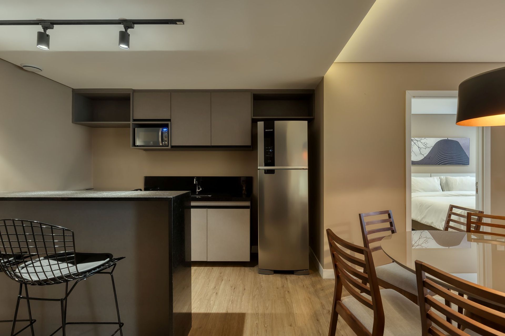 Uma cozinha com geladeira de aço inoxidável e mesa de jantar e cadeiras.