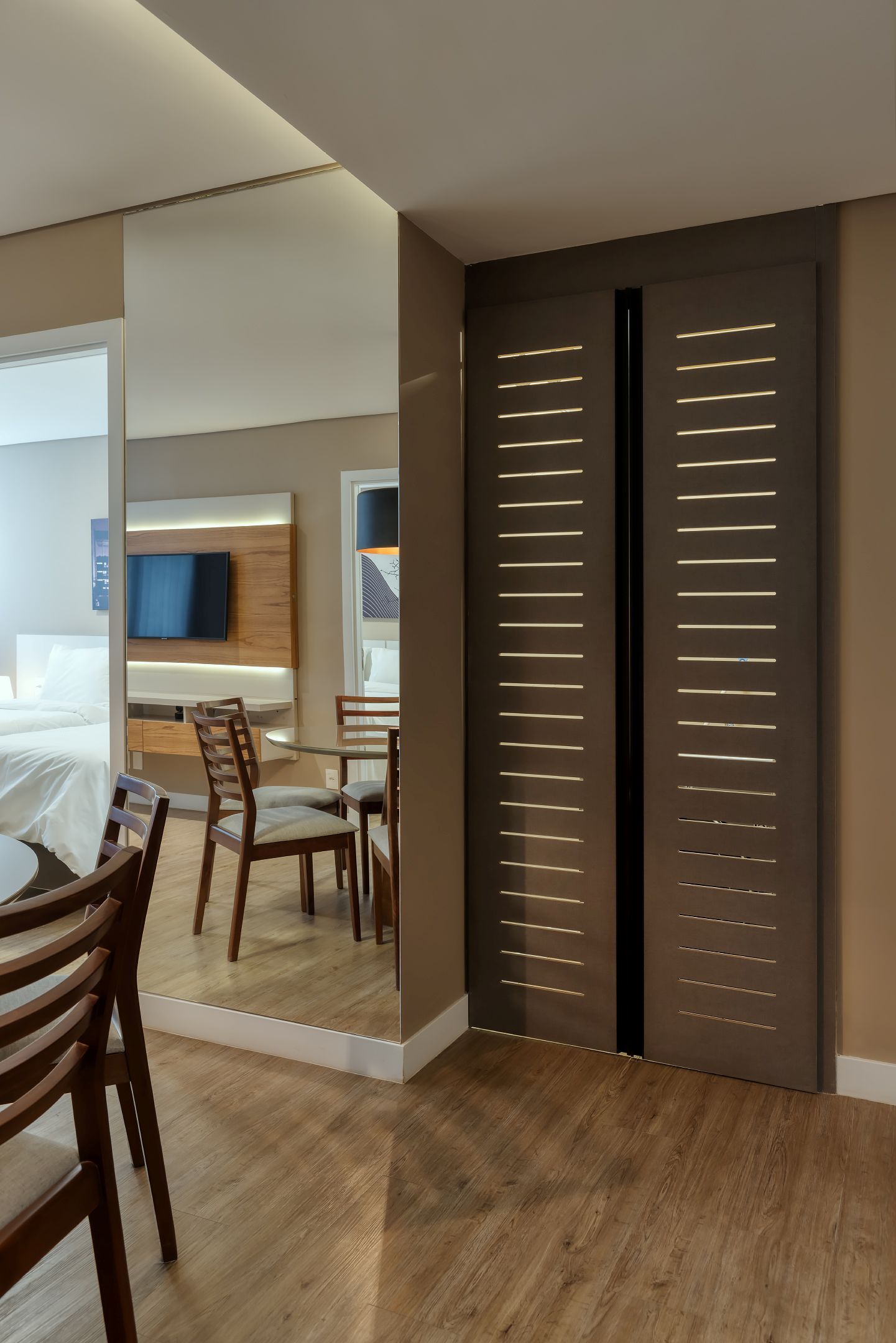 Uma sala com mesa de jantar, cadeiras e uma porta de correr.