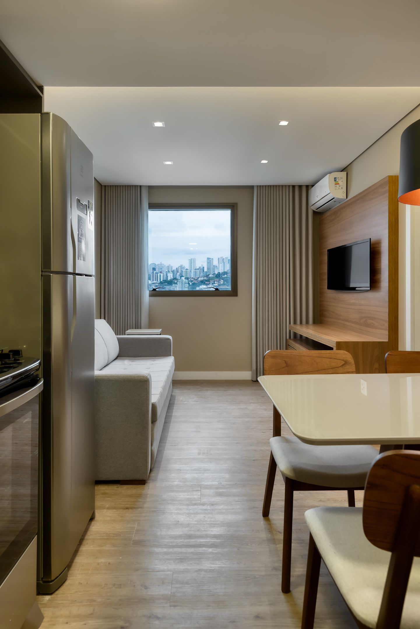 Uma sala de estar com um sofá, mesa, cadeiras e uma geladeira.