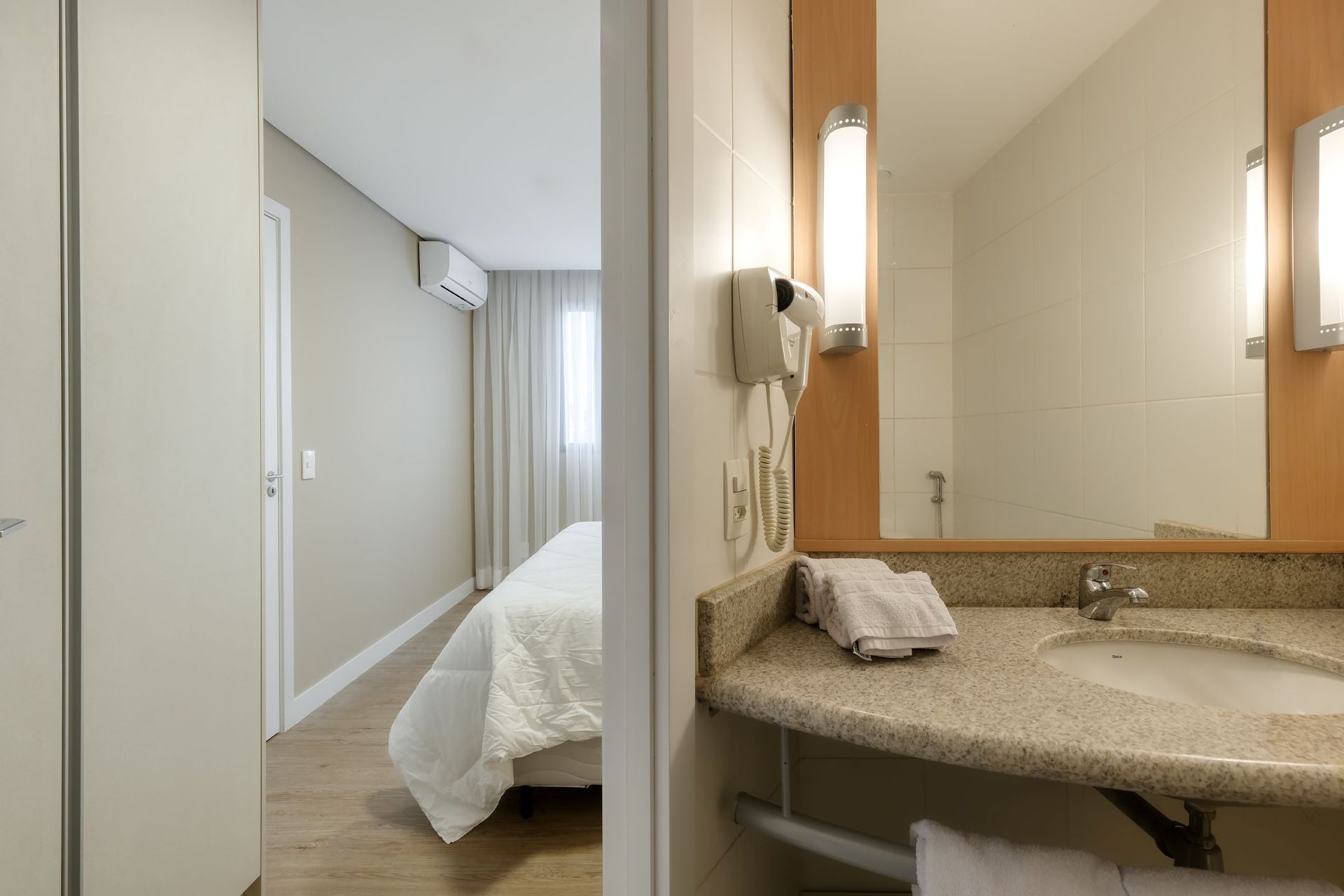 Um banheiro em um quarto de hotel com uma pia e um espelho.