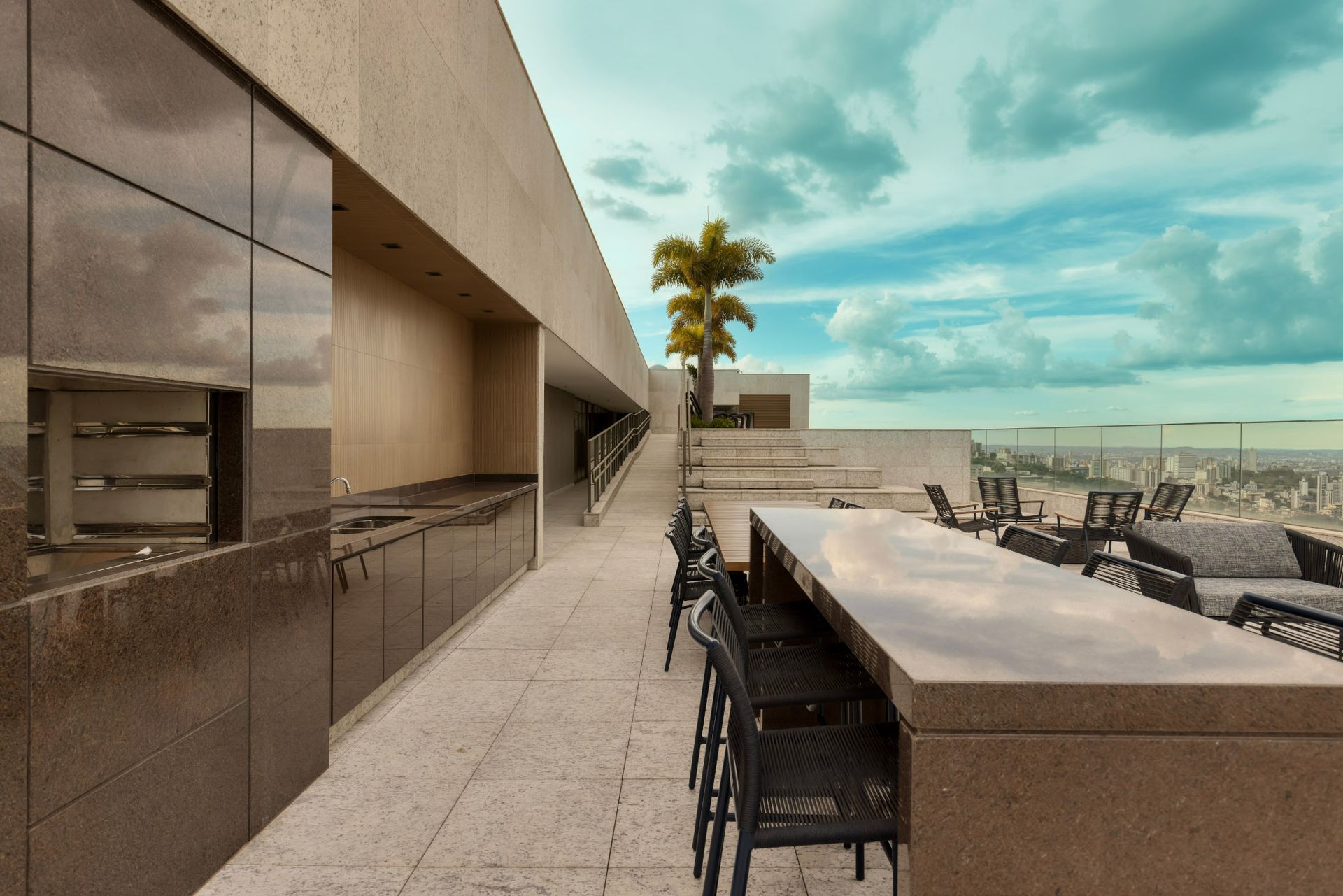 Um pátio com uma mesa longa e cadeiras e uma palmeira ao fundo