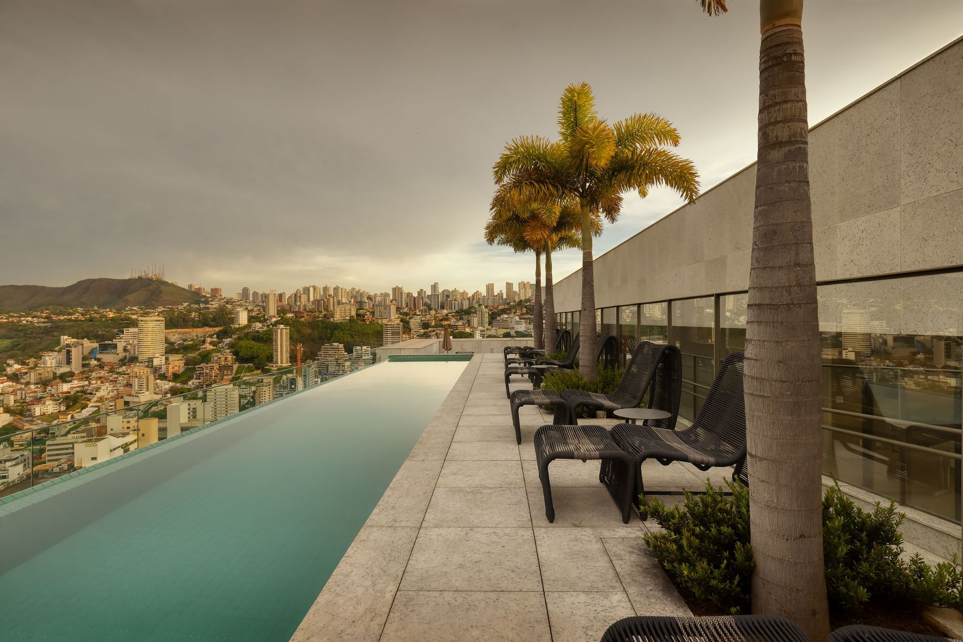 Há uma piscina no telhado de um prédio com vista para a cidade.