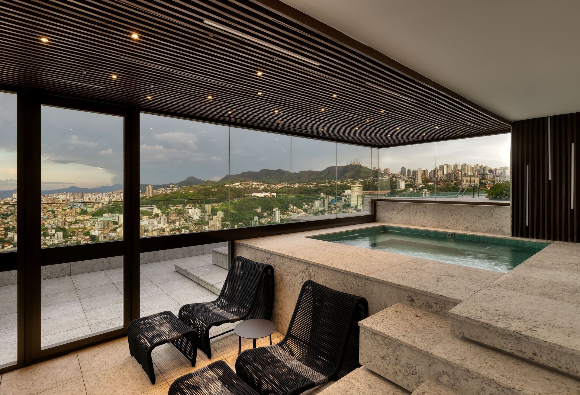 Um quarto com piscina e cadeiras e vista para a cidade