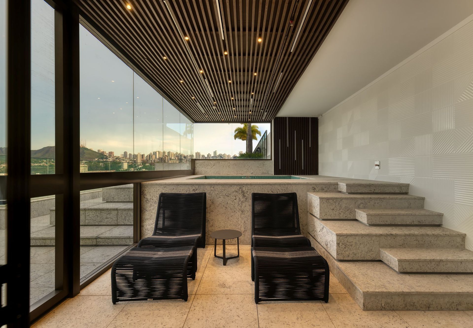 Uma sala com duas espreguiçadeiras e escadas que levam a uma banheira de hidromassagem.