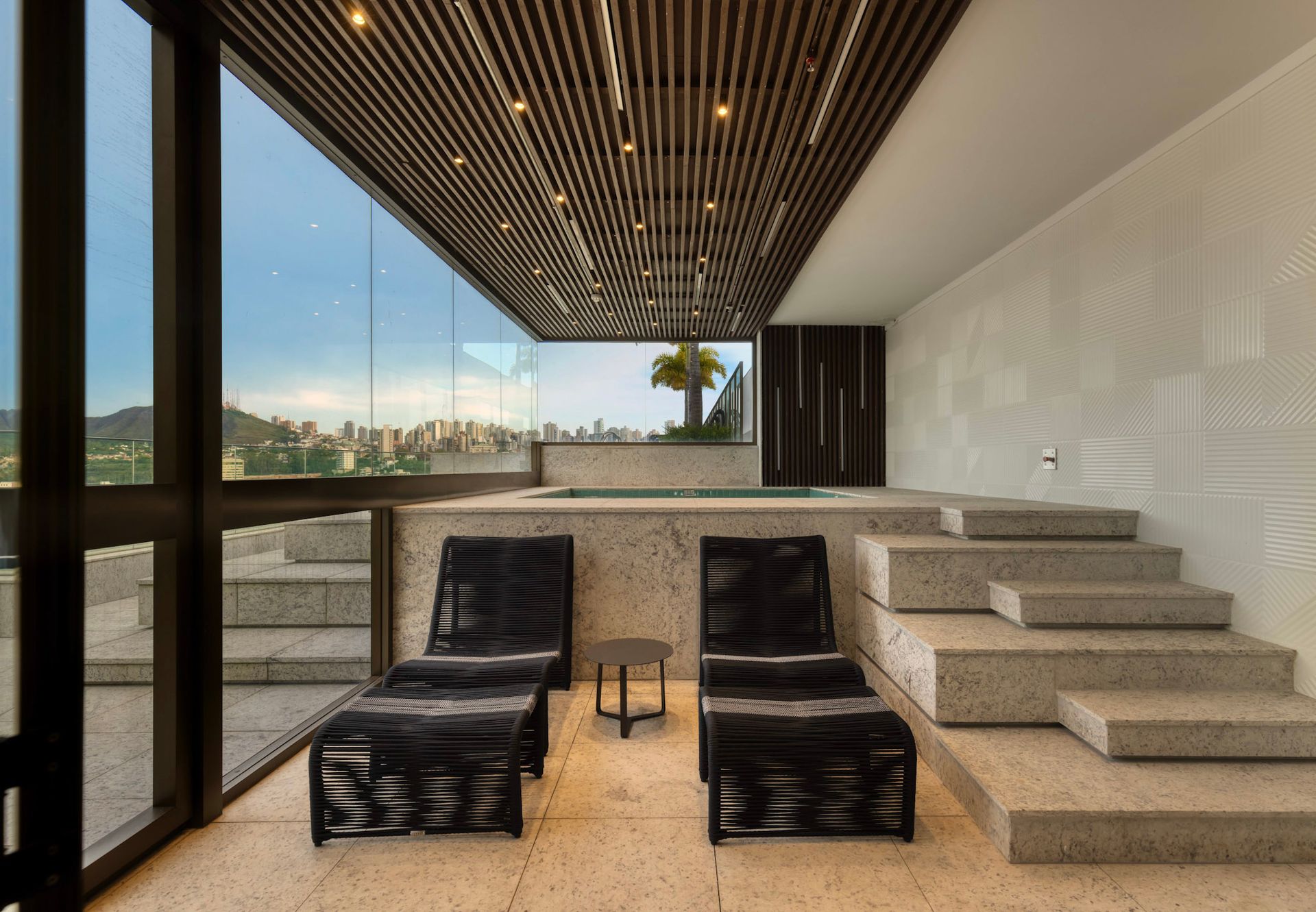 Uma sala com duas espreguiçadeiras e escadas que levam a uma banheira de hidromassagem.