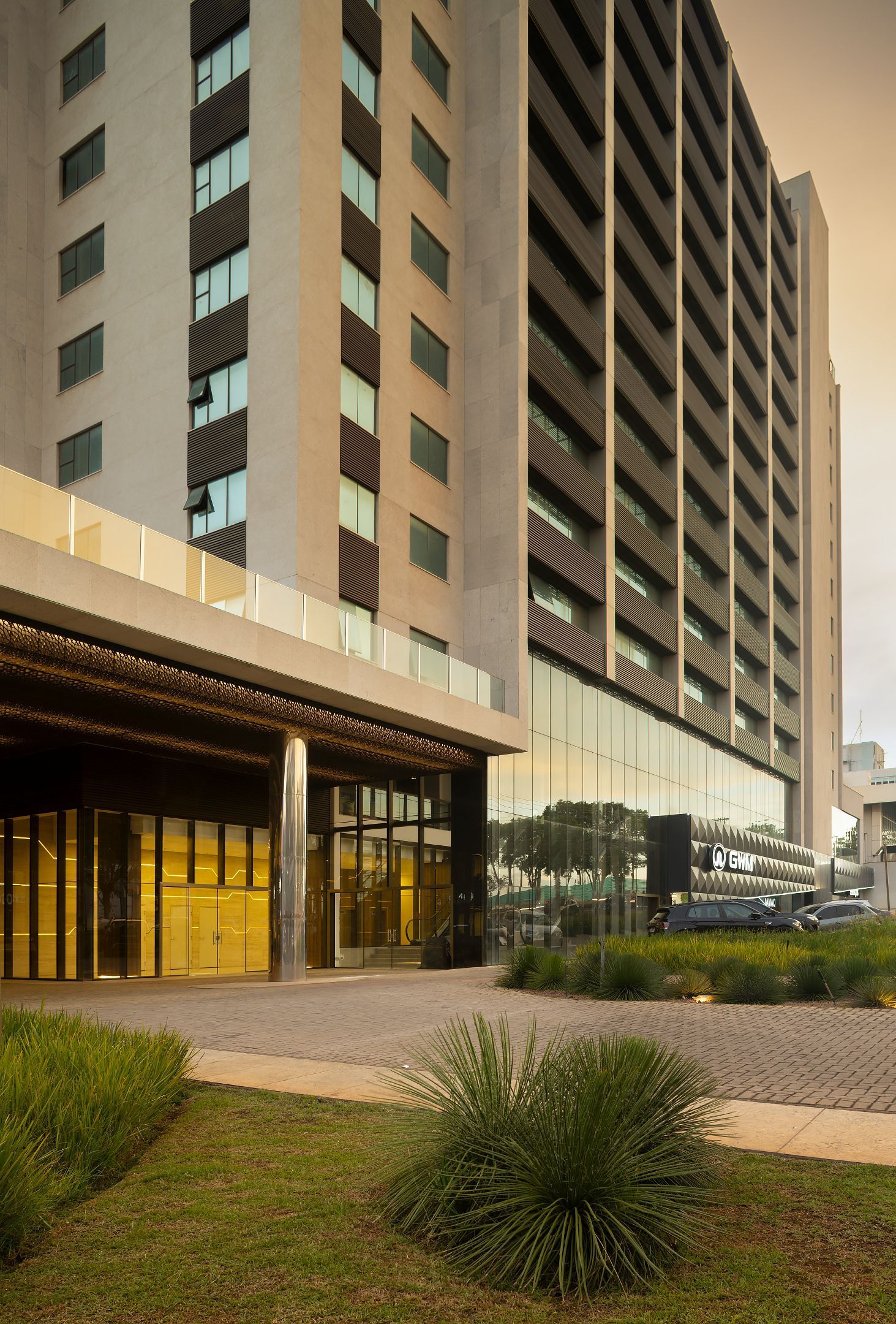 Um grande edifício com muitas janelas cercado por grama e arbustos.