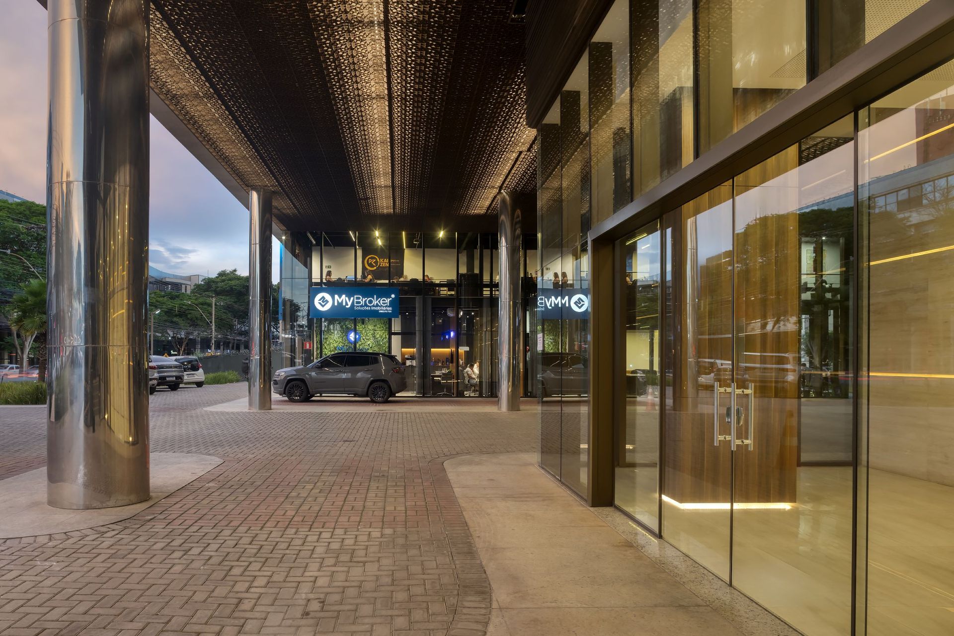 Um carro está estacionado sob um toldo em frente a um prédio.