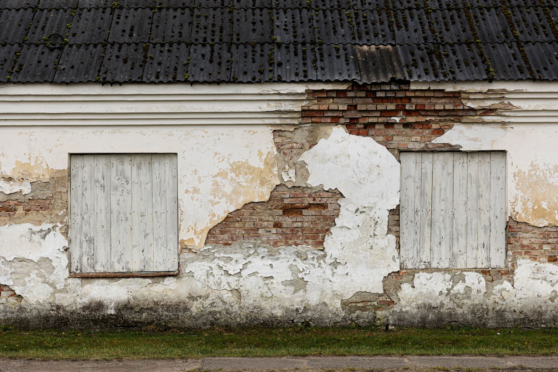 A brick building with a white wall and two windows.