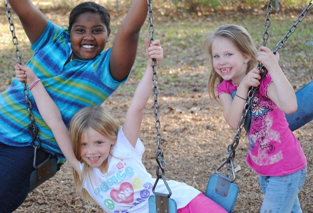 Young, smiling girls playing on swings