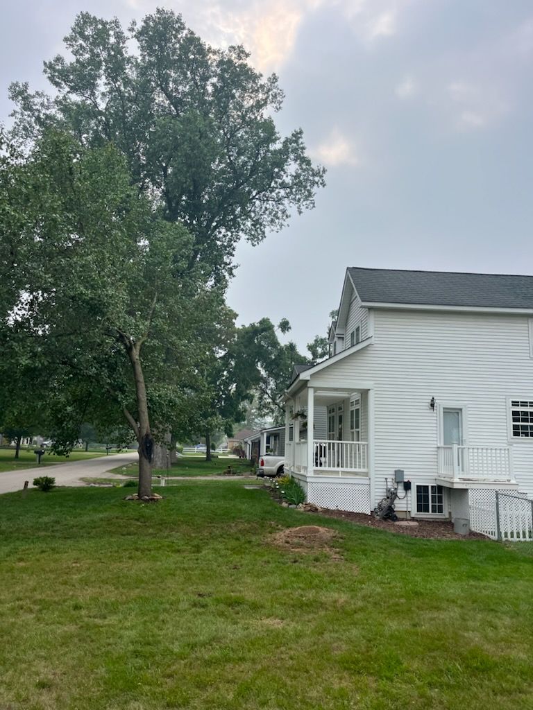 A white house with a porch and a tree in front of it