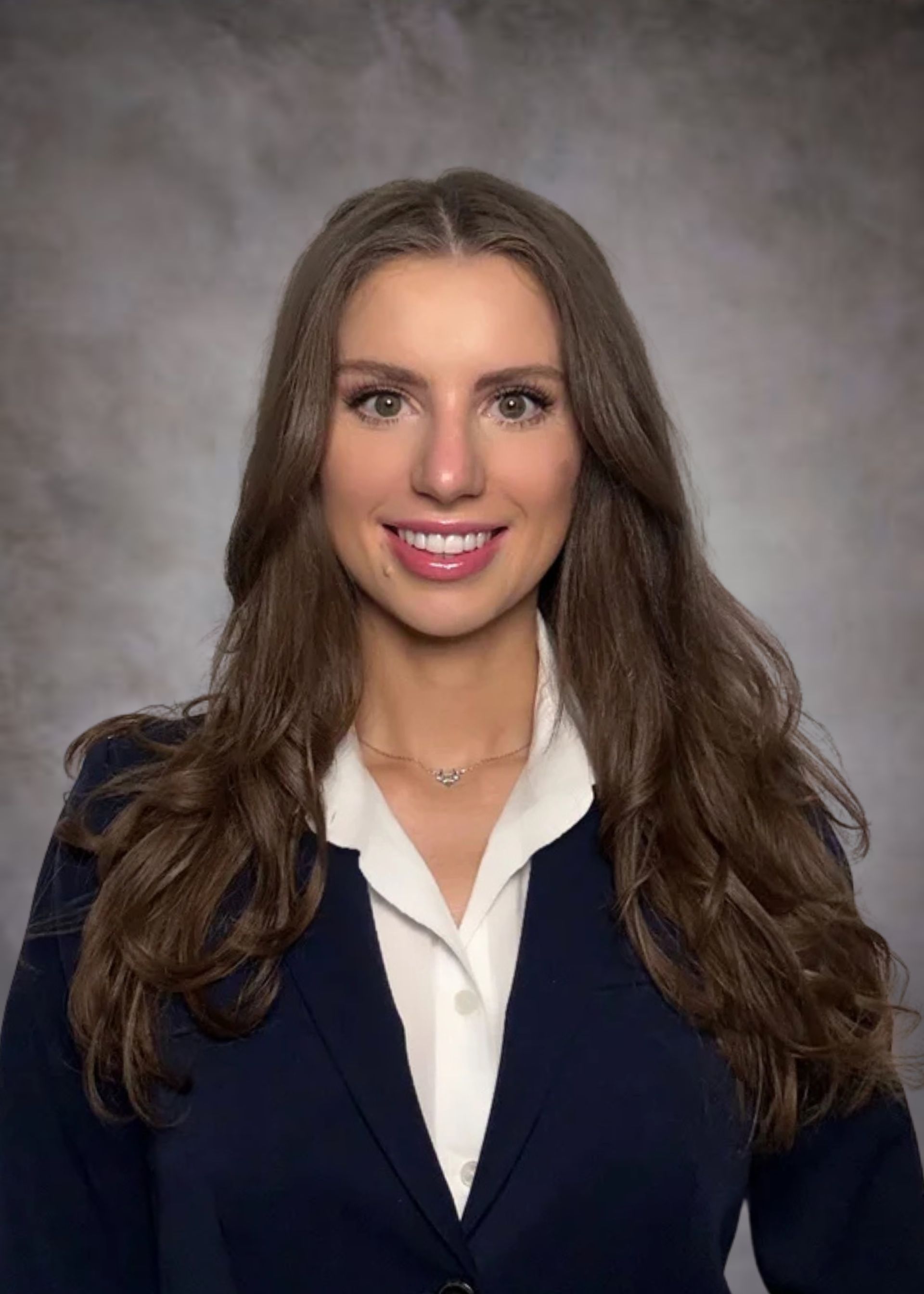 A woman in a suit and white shirt is smiling for the camera.