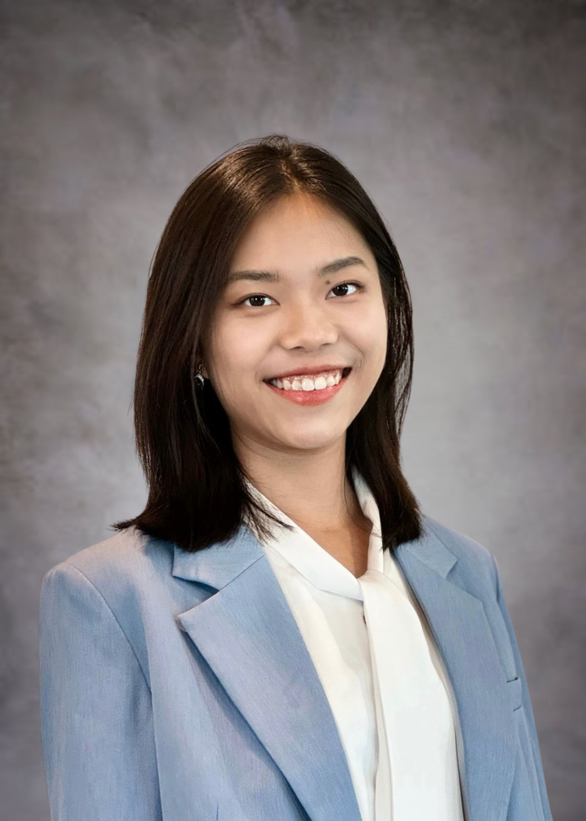 A woman in a blue jacket and white shirt is smiling for the camera.