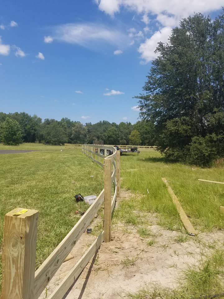 Newly built wooden fence in a grassy field on a sunny day.