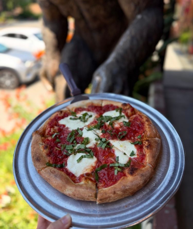 A wooden platter holds several club sandwich triangles, a pile of french fries, and a small bowl of ketchup.