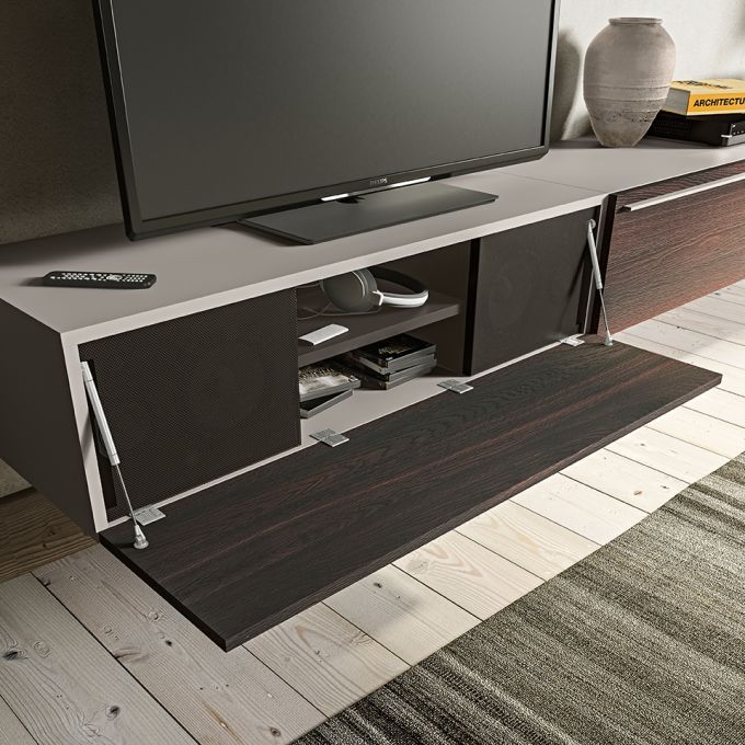 Un televisore è posizionato sopra un mobile porta TV in legno con la porta aperta.