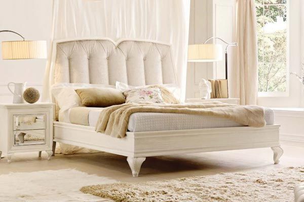 Una camera da letto con un letto, un comodino, una lampada e una finestra.