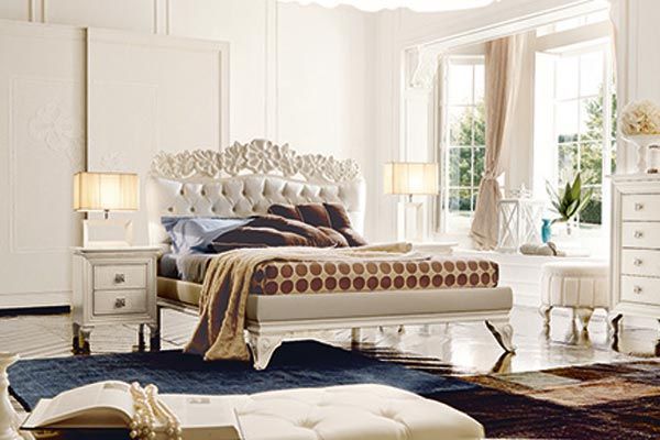 Una camera da letto con un letto, un comodino, una cassettiera e un pouf.