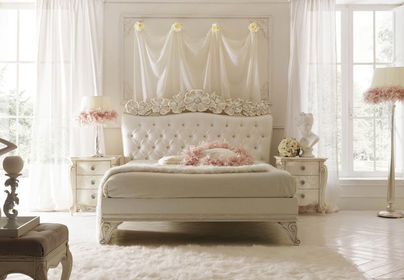 Una camera da letto con un letto bianco e cuscini rosa