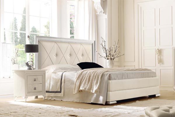 Una camera da letto con un letto, un comodino, una lampada e una finestra.