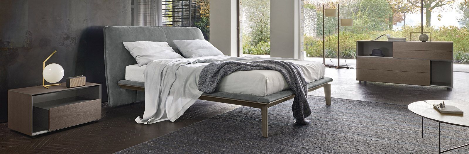 Una camera da letto con un letto, un comodino, una cassettiera e un tappeto.