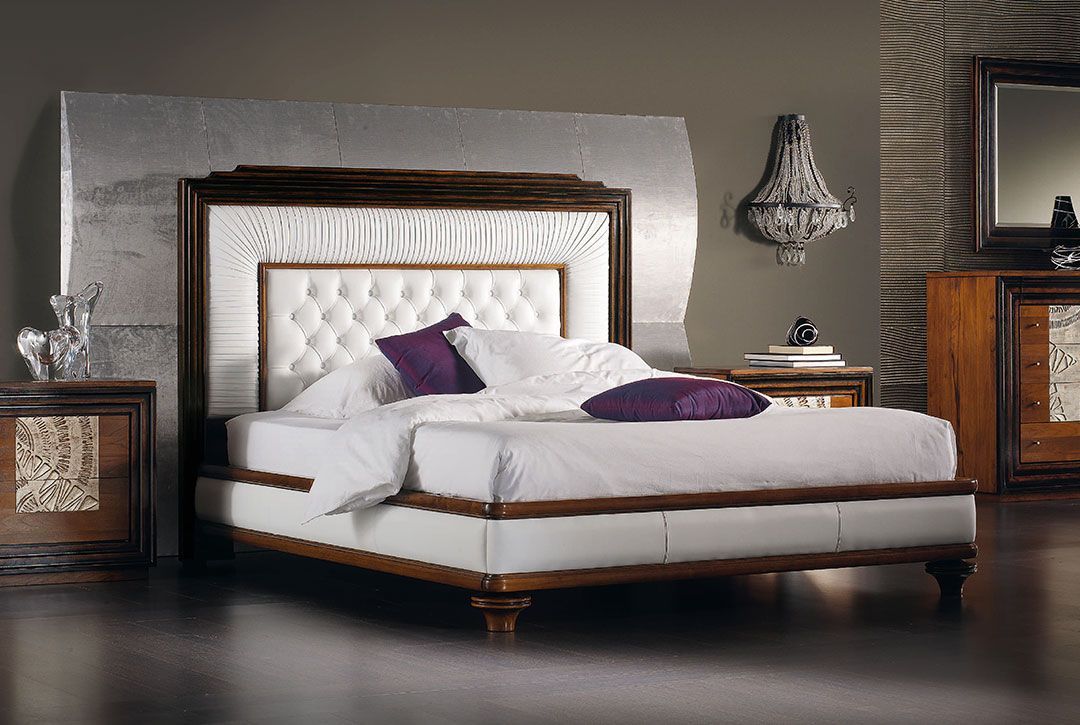 Un letto con lenzuola bianche e cuscini viola in una camera da letto