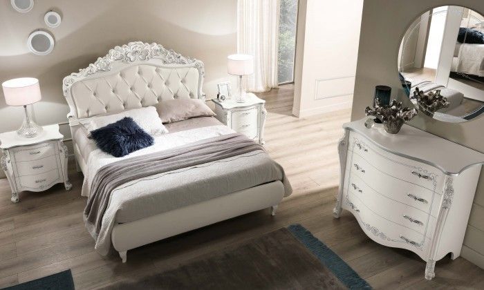 Una camera da letto con letto, cassettiera, comodino e specchio.