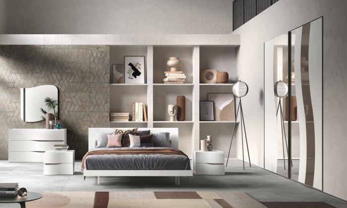 Una camera da letto con letto, cassettiera, comodino, specchio e scaffali.