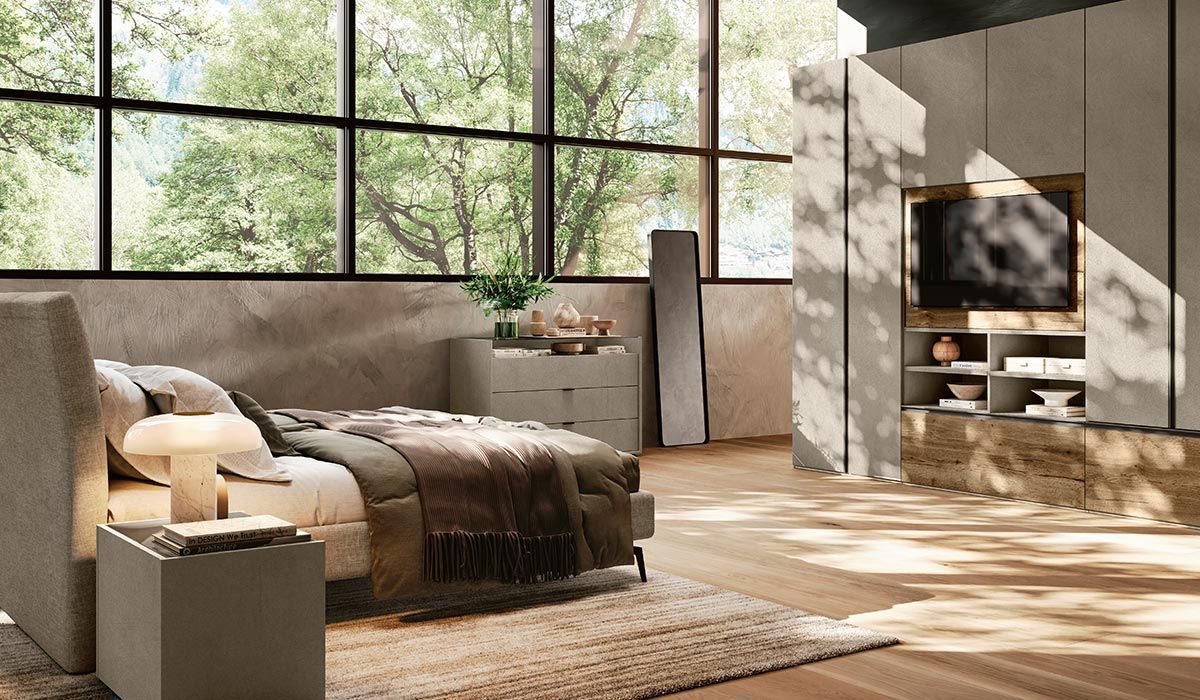 Una camera da letto con letto, comodino, televisione e grandi finestre.