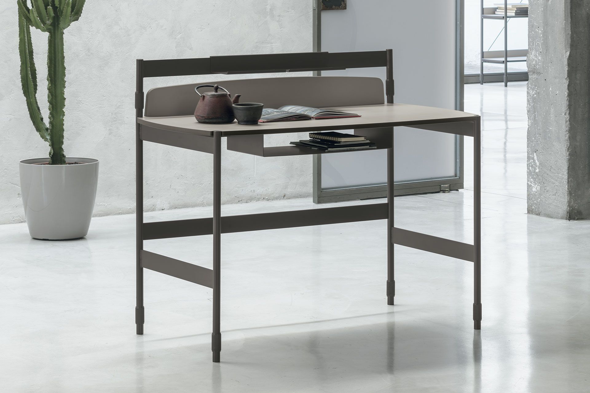Una scrivania in una stanza con una pianta in vaso sullo sfondo