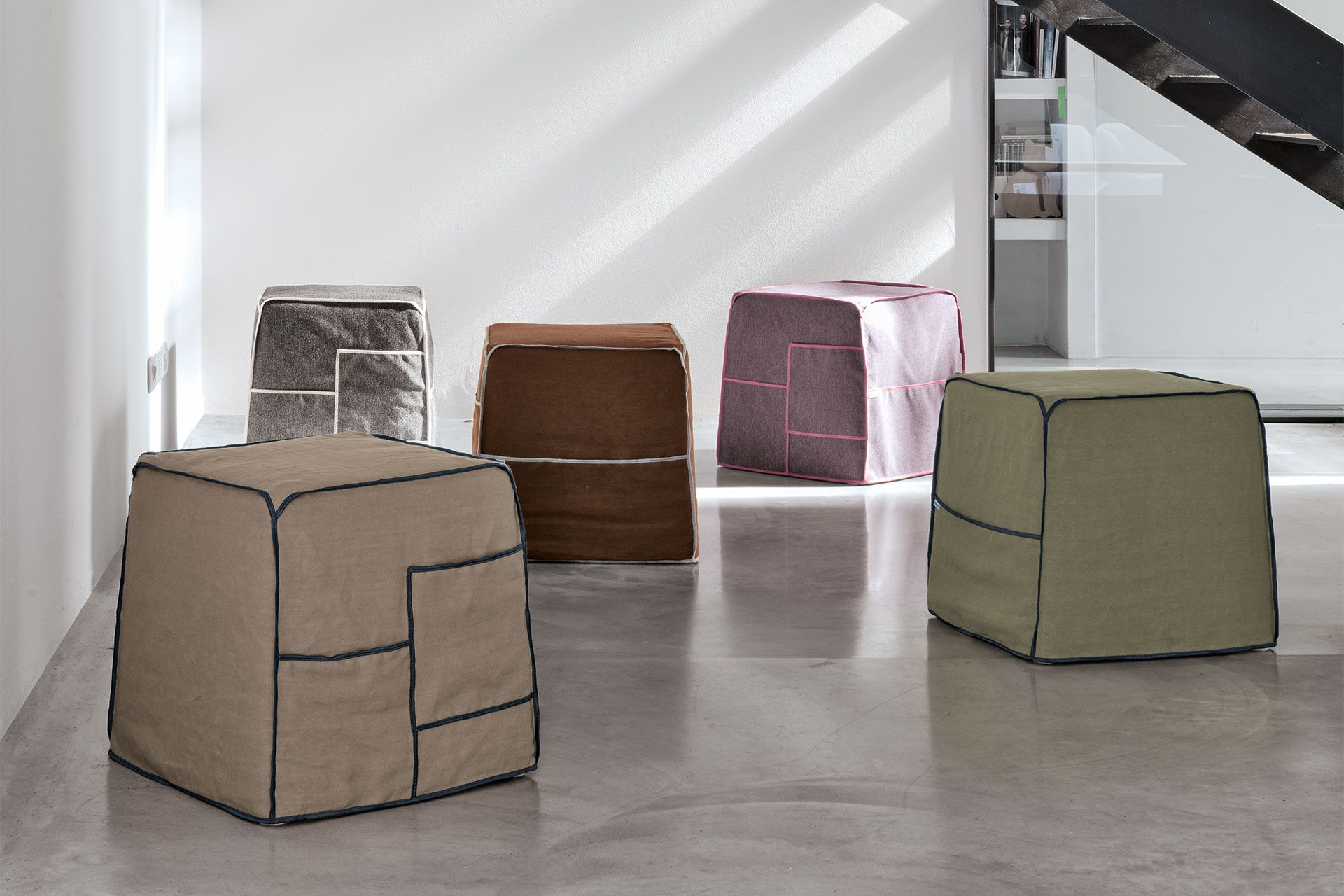 Un gruppo di pouf sono allineati su un pavimento di cemento