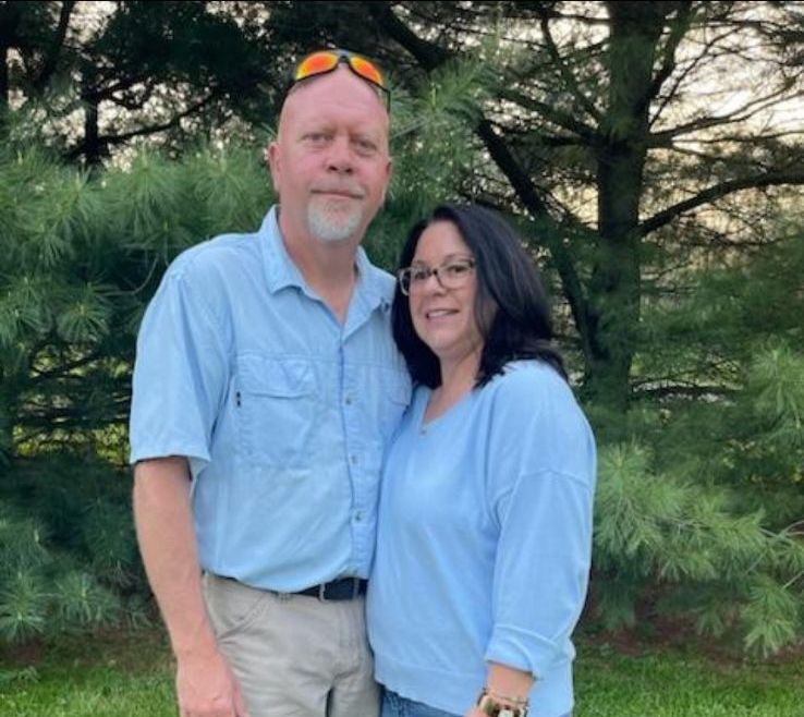 A man and a woman are posing for a picture in a living room.