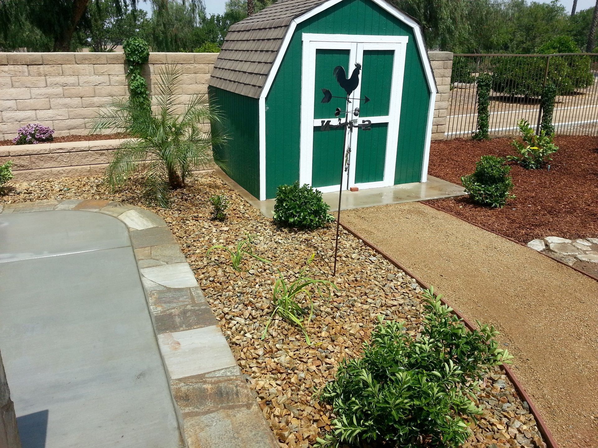 A green barn shaped shed with a chicken on the door