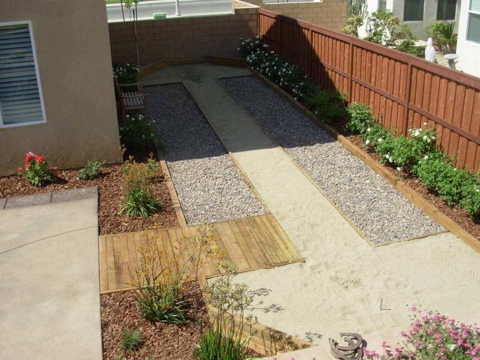 A driveway leading to a house with a wooden fence
