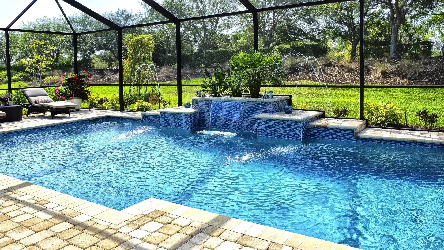 Pool with blue tile and tiered waterfall, surrounded by screening and lawn.