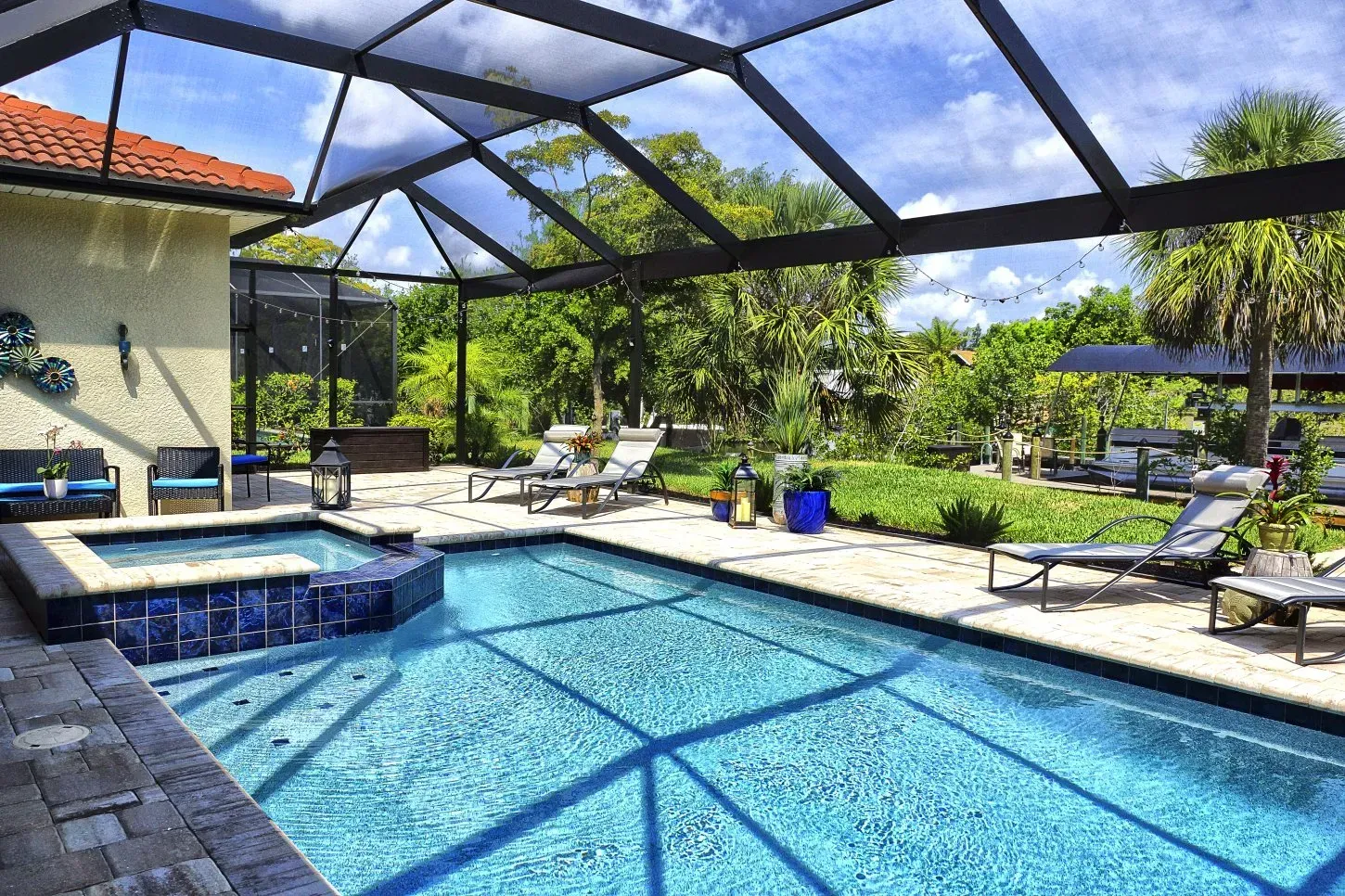 Pool area with screen enclosure, lounge chairs, and lush landscaping.
