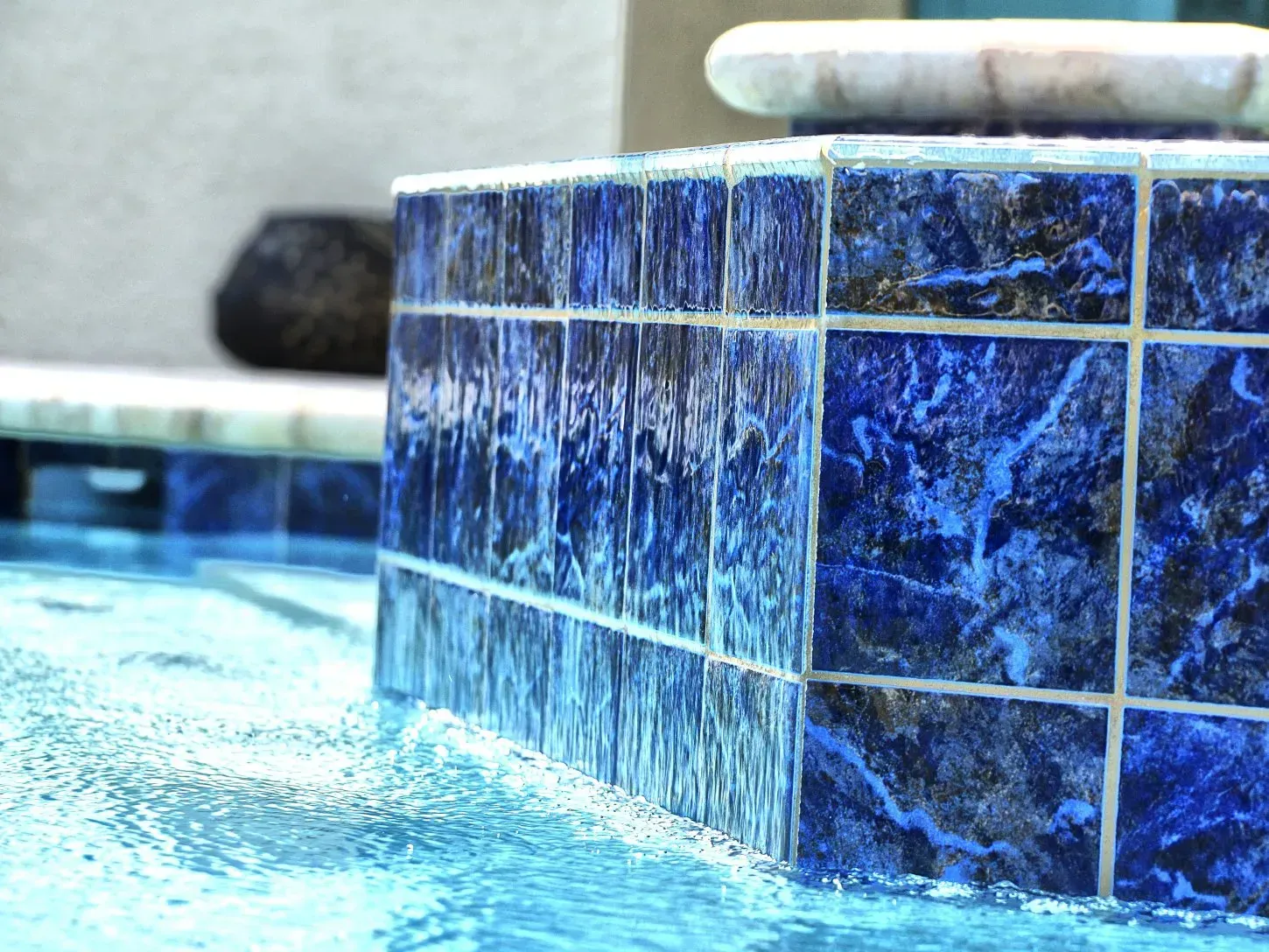 Blue tiled water feature with water cascading into pool.