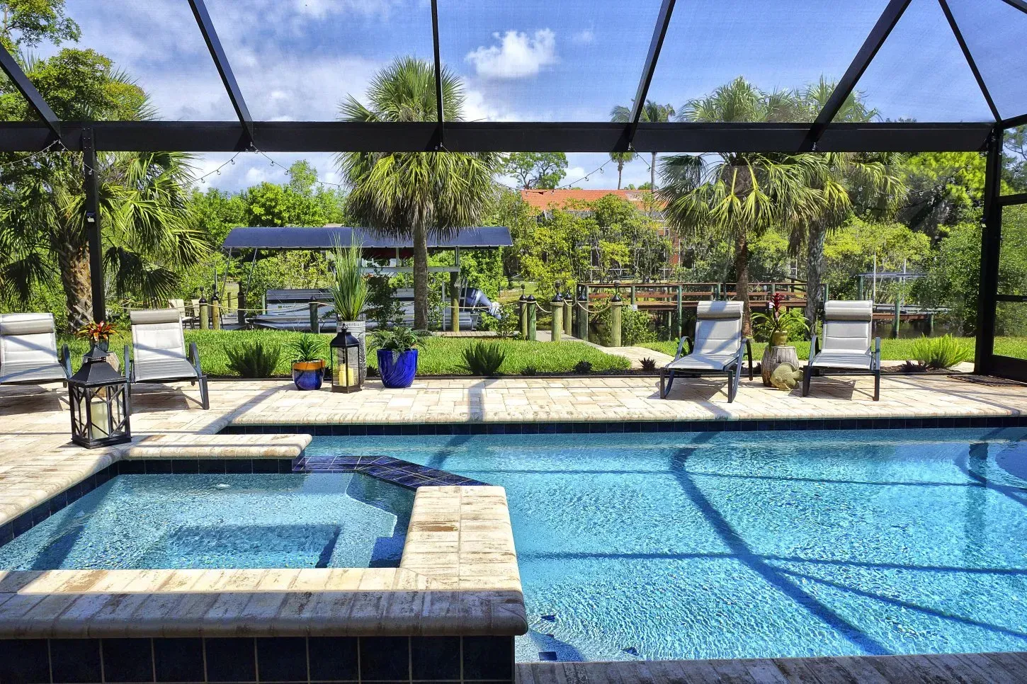 Pool area with a pool, lounge chairs, and a view of trees and a garden.