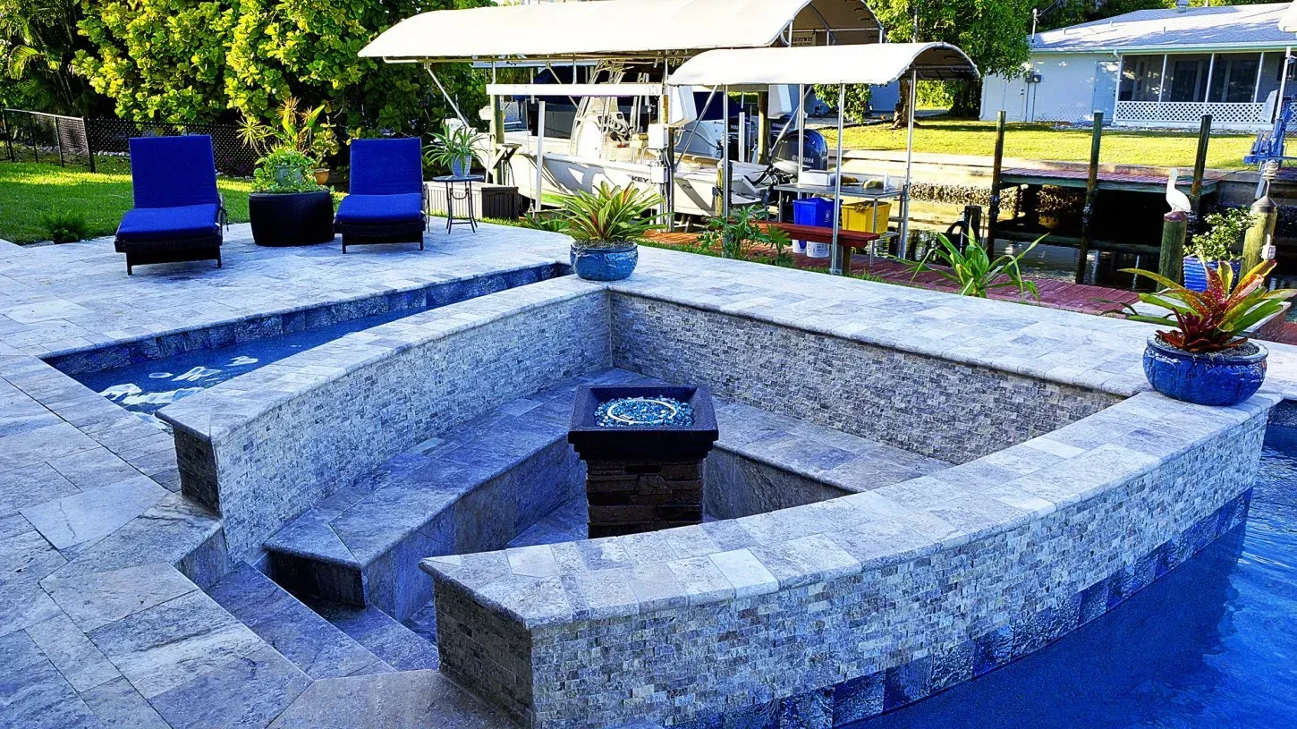 Pool with fire pit, seating, blue chairs, and plants. Outdoor setting.
